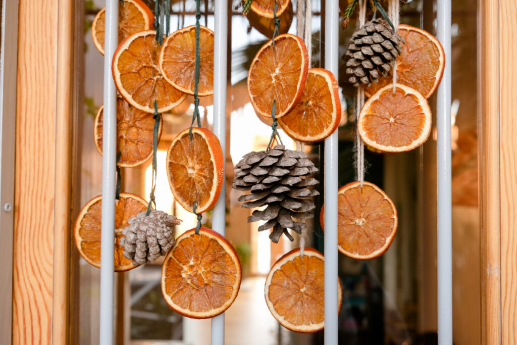 DIY Christmas garland made with dried orange slices and pinecones hanging from natural twine.