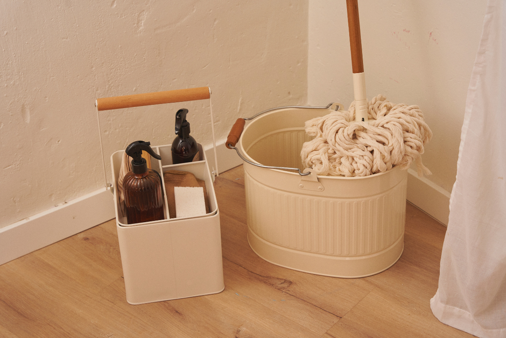 Organized cleaning supplies with spray bottles, cloths, a mop and bucket for an easy weekly cleaning schedule.