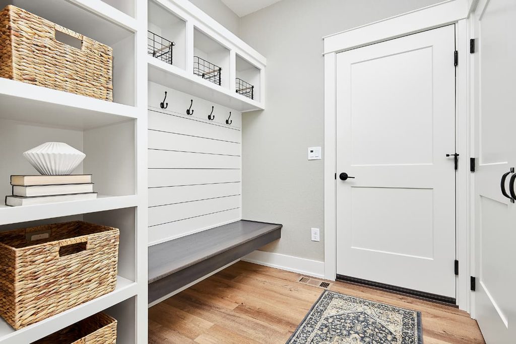 Organized home entryway with storage baskets, wall hooks, and a wooden bench.