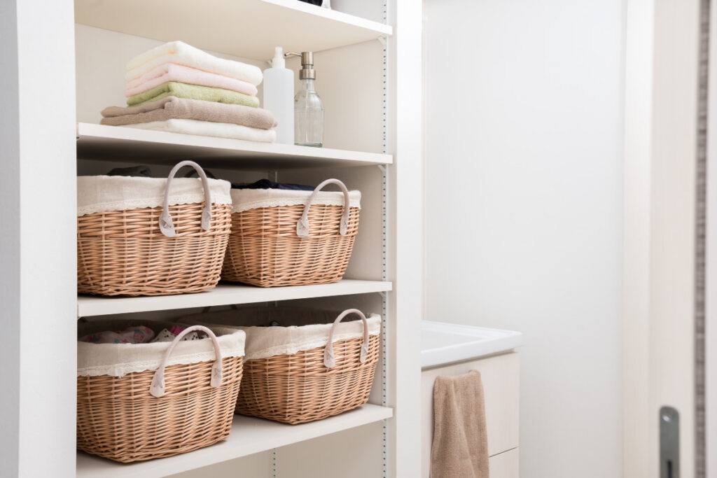 Small space organization ideas using wicker storage baskets and open bathroom shelves for towels and toiletries.